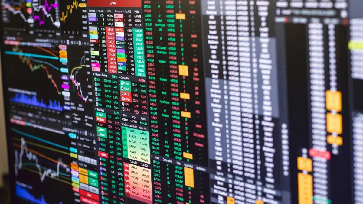 A market data terminal showing dense price grids, order rows and candlestick charts on a dark screen
